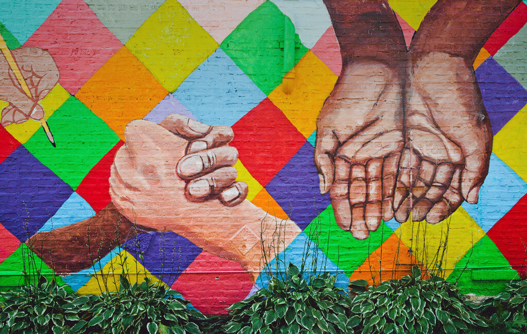 Mural depicting hands of many colors against a bright checkered background