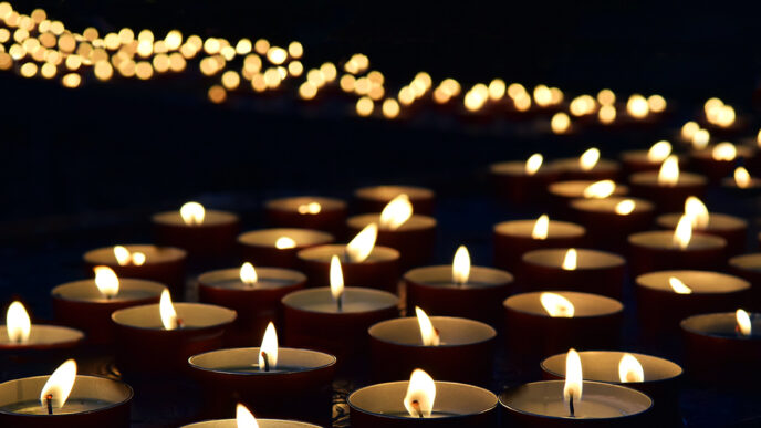 A path of lit candles against a dark background.