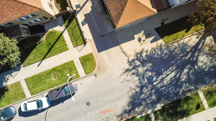 Aerial view of a residential street with cars parked along a curb.